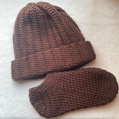 two brown knitted hats sitting on top of a white blanket next to each other