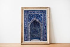 an ornate blue and white tile work in a wooden frame on top of a table