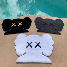 four pieces of felt with faces drawn on them next to a swimming pool