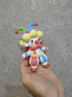 a hand holding a small toy clown on it's finger