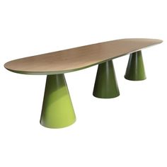 an oval shaped table with three green pedestals