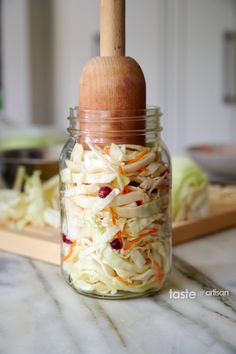 a jar filled with coleslaw sitting on top of a counter next to a cutting board