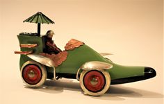 an old fashioned toy car with a man in the driver's seat and umbrella on top