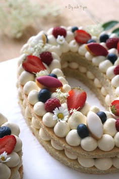 a cake with white frosting and strawberries on top is decorated like the letter o