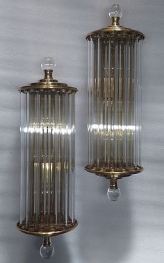 two glass and brass wall sconces with lights on each side, hanging from the ceiling