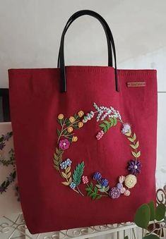 a red bag with flowers on it sitting next to a white shelf and some plants