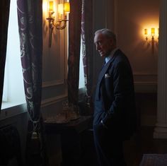 a man in a suit standing next to a window