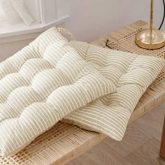 a bed sitting on top of a wooden table next to a lamp and windowsill