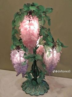 a vase filled with pink and purple flowers on top of a white tablecloth covered table