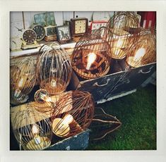 many cages with lit candles in them sitting on the grass next to clocks and other items