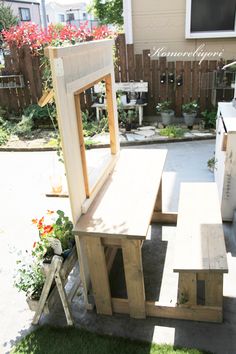 a wooden bench sitting in the middle of a yard next to a table and chairs