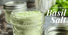 two jars filled with basil salt sitting on top of a table