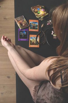 a woman sitting on top of a yoga mat next to cards and necklaces in front of her