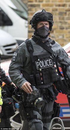 two police officers in full riot gear walking down the street with their hands on their hipss