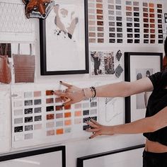 a woman pointing to a wall with pictures on it and an animal head hanging from the wall