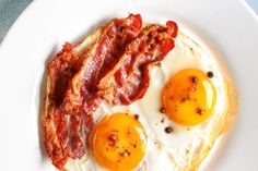 two eggs and bacon on a white plate