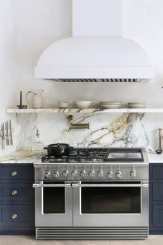 a stove top oven sitting inside of a kitchen next to a wall mounted range hood