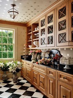 a kitchen filled with wooden cabinets and black and white checkered flooring next to a window