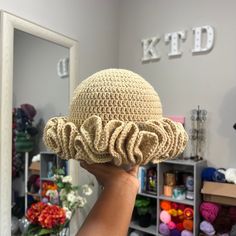 a person holding up a crocheted hat in front of a mirror