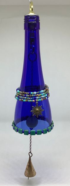 a blue glass bell with bells attached to it's sides and beads on the bottom