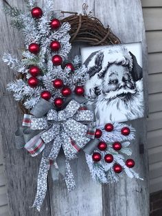 a christmas wreath is hanging on the side of a wooden door with red and silver ornaments