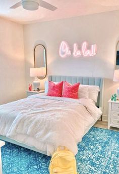 a white bed sitting in a bedroom under a neon sign