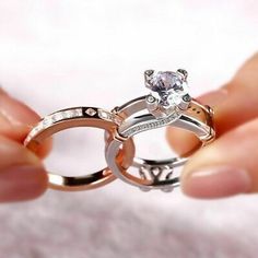 two people holding their wedding rings with the ring being held in front of each other