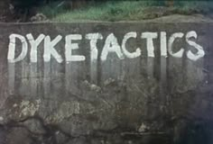 the word dyketactics written in white chalk on a wall