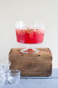 a wooden table topped with two glasses and a bowl filled with liquid on top of it