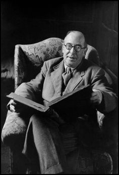 an old photo of a man sitting in a chair reading a book