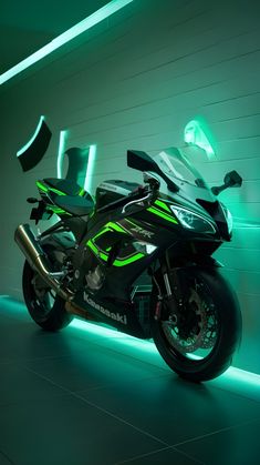 a green motorcycle parked in front of a white wall with neon lights on the side