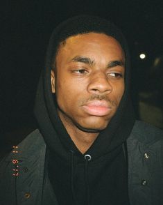 a man wearing a black hoodie looking at the camera with an intense look on his face