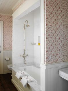 a bathroom with pink and white wallpaper, bathtub, sink and toilet in it