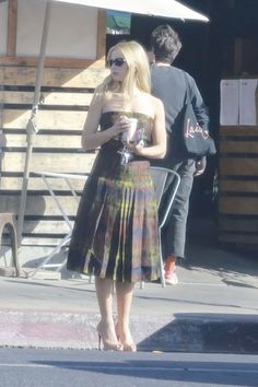 a woman in a dress is standing on the sidewalk