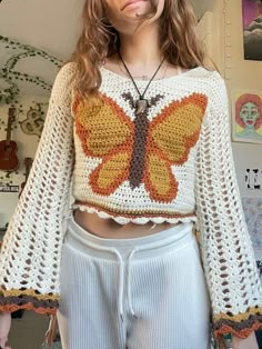 a woman wearing white shorts and a crochet top with a butterfly on it