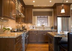 a kitchen with wooden cabinets and granite counter tops, along with black leather chairs in front of the sink