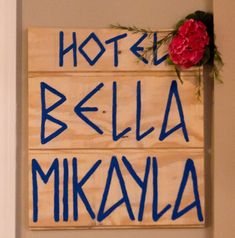 a wooden sign that says hotel bella mikaya with blue writing on it