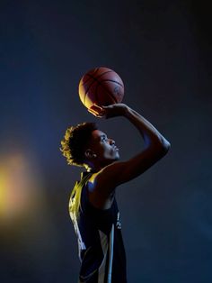 a young man holding a basketball in his right hand and looking up at the sky