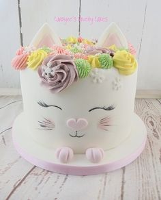 a white cake decorated with flowers and a cat's face