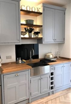 a kitchen with gray cabinets and wooden counter tops