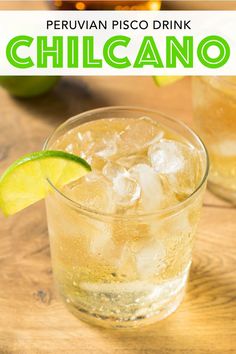 a glass filled with ice and lime on top of a wooden table