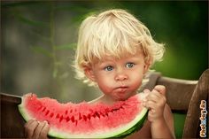 a young boy eating a piece of watermelon