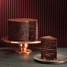 a chocolate cake sitting on top of a table next to a plate with a slice cut out