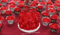 a table topped with lots of red cupcakes