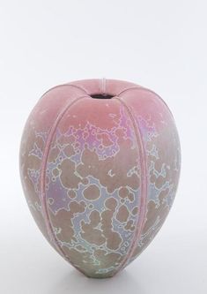 a pink and blue vase sitting on top of a white table