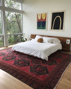 a large bed sitting on top of a wooden floor next to a tall glass window