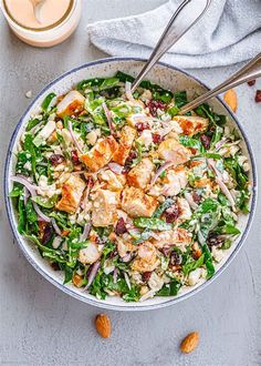 a bowl filled with salad next to a cup of coffee and two spoons on the side