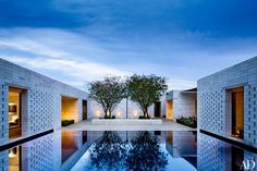 an empty swimming pool with trees in the middle and sky reflected on the water at dusk