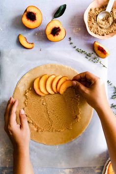 a person is placing sliced peaches on top of a cake