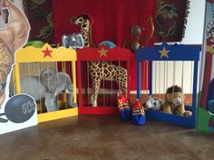 stuffed animals and toys are displayed on the floor in front of a red curtained window